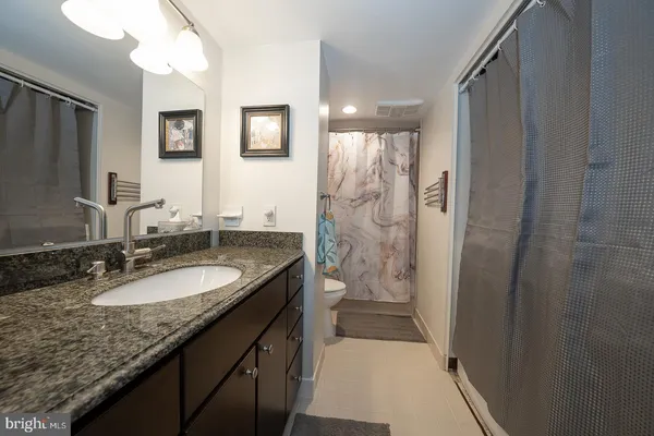 a bathroom with a granite countertop sink a mirror a shower and a vanity