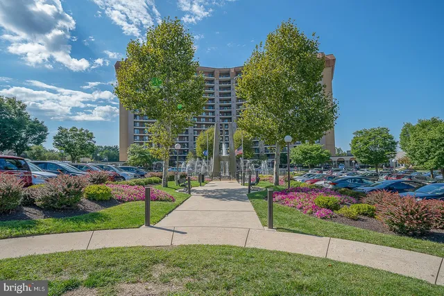a front view of a multi story residential apartment building with yard and green space