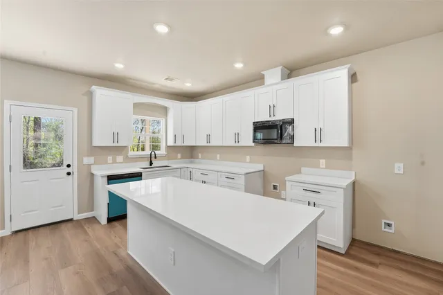 a large white kitchen with lots of counter space sink and appliances