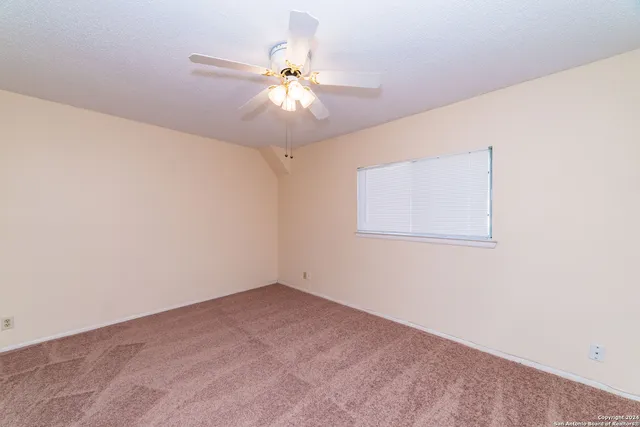 an empty room with a window and a fan