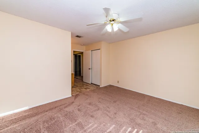 an empty room with chandelier fan