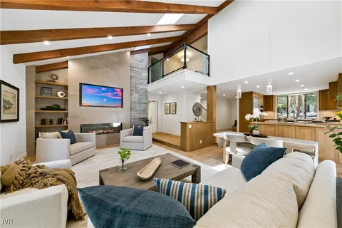 a living room with furniture kitchen view and a chandelier