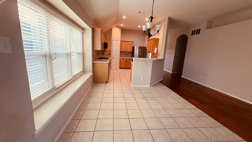 5970 Dustin Trail Frisco, TX 75034 - Photo 14 of 31 Kitchen and dining area featuring light-toned tile flooring, honey-toned cabinetry, and a peninsula with a breakfast bar