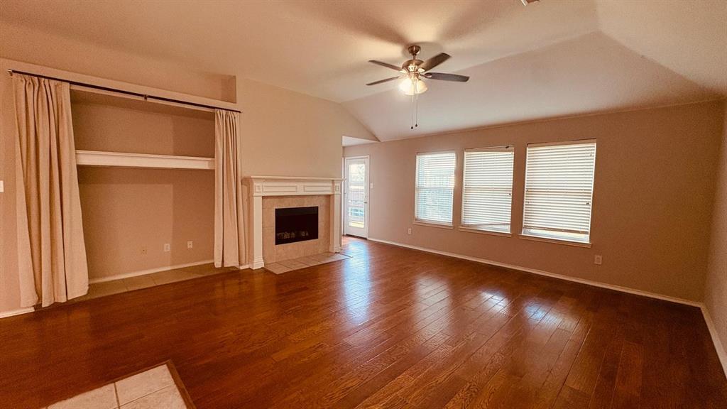 5970 Dustin Trail Frisco, TX 75034 - Photo 17 of 31 Spacious living area featuring wood-finish flooring, vaulted ceilings, and a built-in fireplace with a decorative mantel