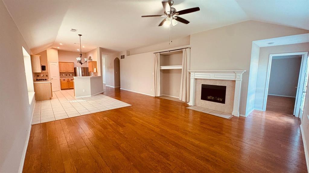 5970 Dustin Trail Frisco, TX 75034 - Photo 18 of 31 Spacious living area featuring wood-finish flooring, a fireplace with a detailed mantel, and an integrated ceiling fan