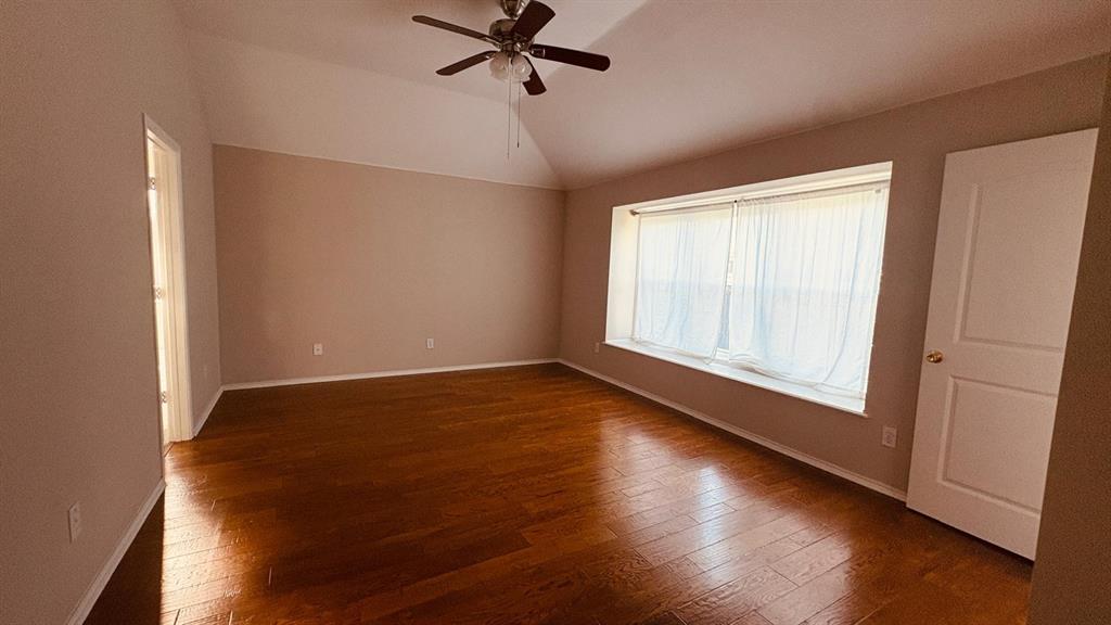5970 Dustin Trail Frisco, TX 75034 - Photo 19 of 31 Spacious room featuring vaulted ceilings, wood-finish flooring, a ceiling fan, and a wide bay window with sheer curtains