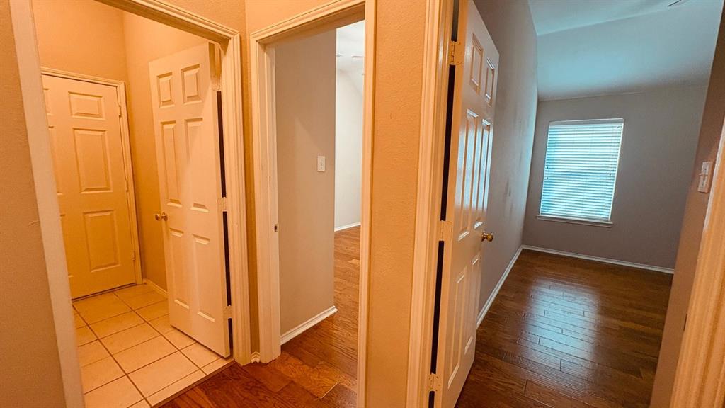 5970 Dustin Trail Frisco, TX 75034 - Photo 22 of 31 Interior hallway with wood-finish flooring extending into a room featuring a window with horizontal blinds and light-colored walls