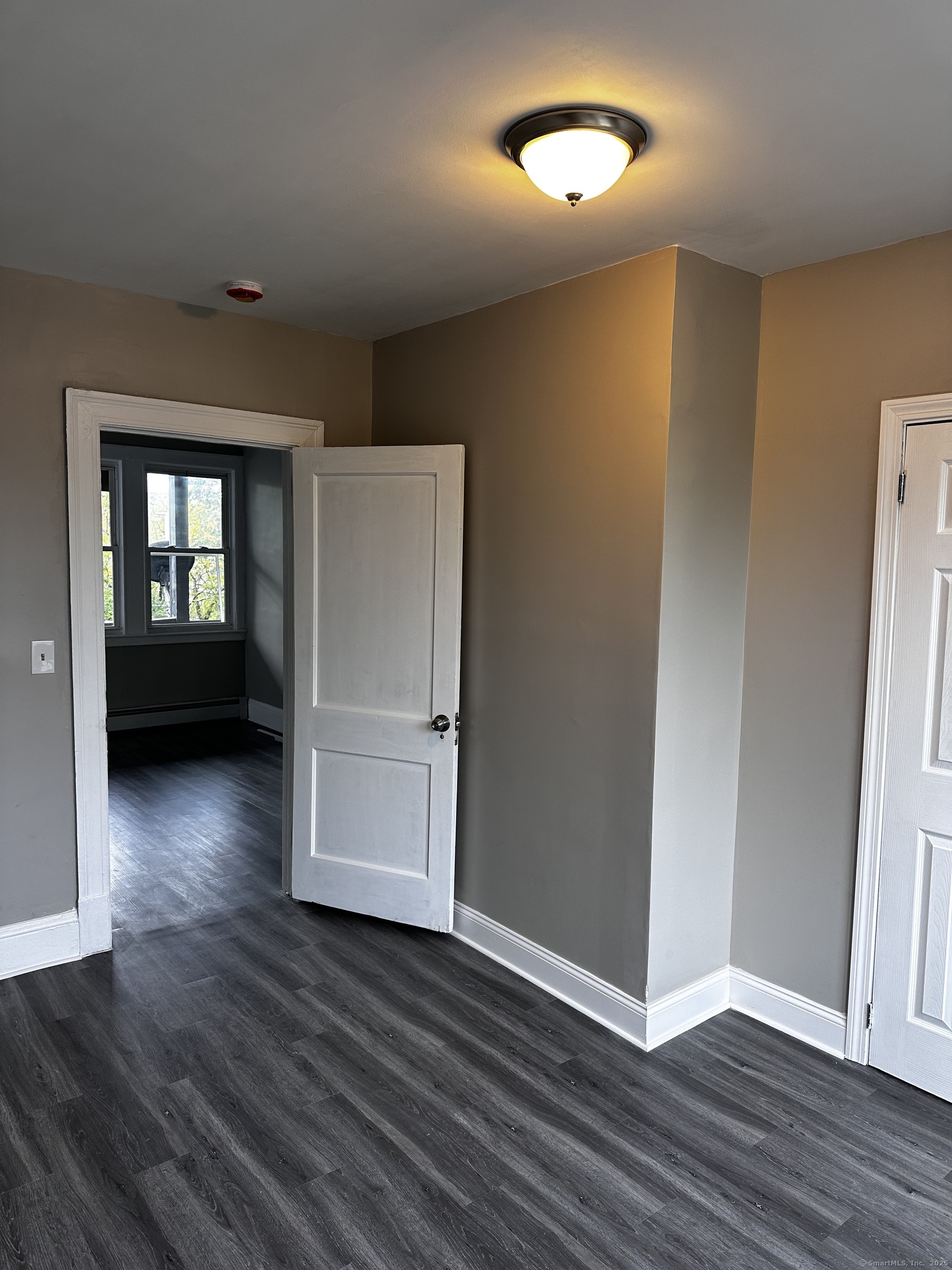an empty room with wooden floor cabinet and windows