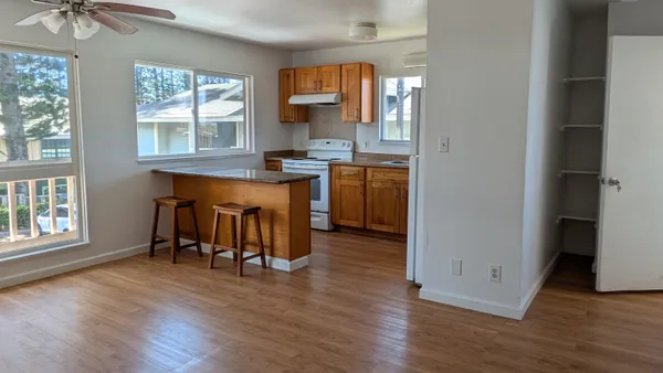 an open kitchen with granite countertop a stove top oven a sink dishwasher and a dining table with wooden floor