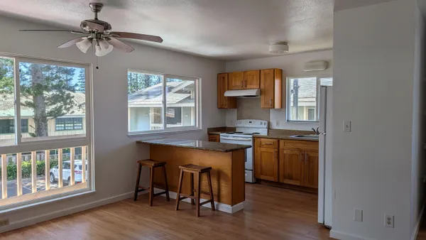 a kitchen with stainless steel appliances granite countertop a stove a refrigerator a sink a dining table and chairs with wooden floor