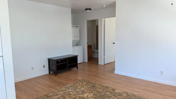an empty room with wooden floor and a sink