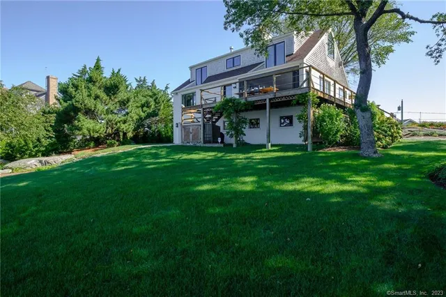 a view of a house with a big yard plants and large trees