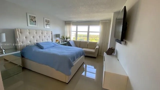 a spacious bedroom with a bed and a flat screen tv