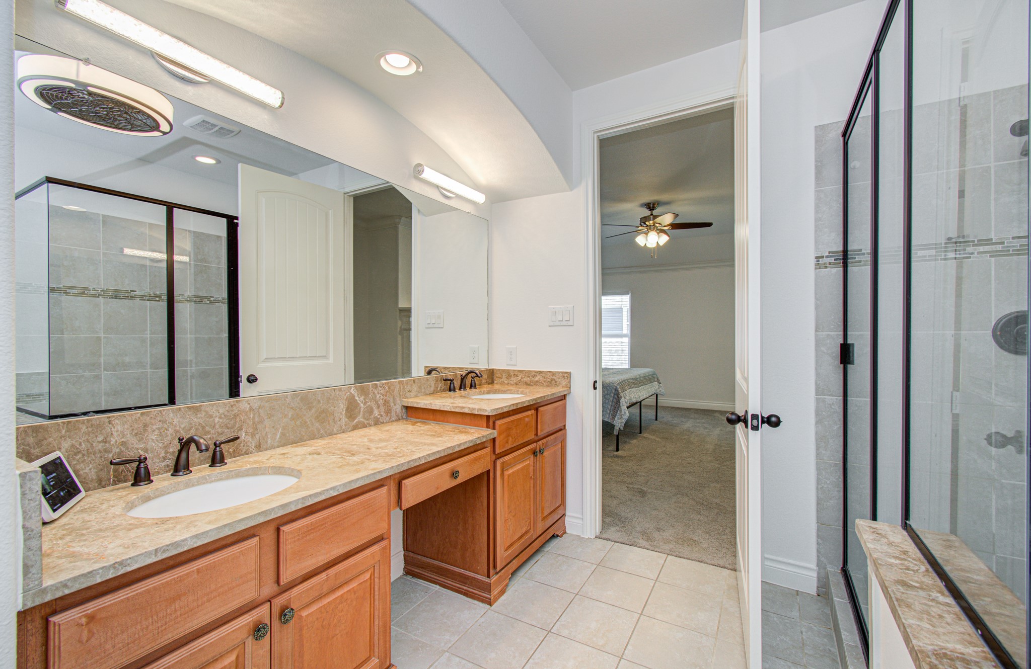 6621 North Main Street Houston, TX 77009 - Photo 18 of 41 Ensuite bath features a modern double vanity with wood cabinetry and marble countertops. It includes a spacious glass-enclosed shower and is connected to a bedroom, offering convenience and style.