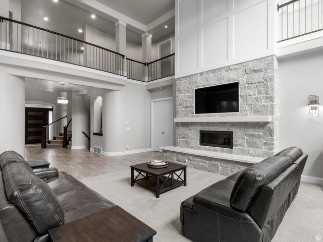 614 East High Lane Alpine, UT 84004 - Photo 33 of 75 Carpeted living room with a stone fireplace, arched walkways, and a high ceiling