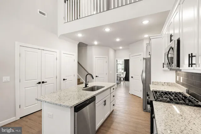 a kitchen with stainless steel appliances granite countertop a sink and a refrigerator