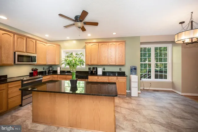 a kitchen with stainless steel appliances granite countertop a refrigerator a sink a stove a oven with a dining table and chairs with wooden floor