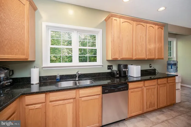 a kitchen with granite countertop white cabinets sink and window