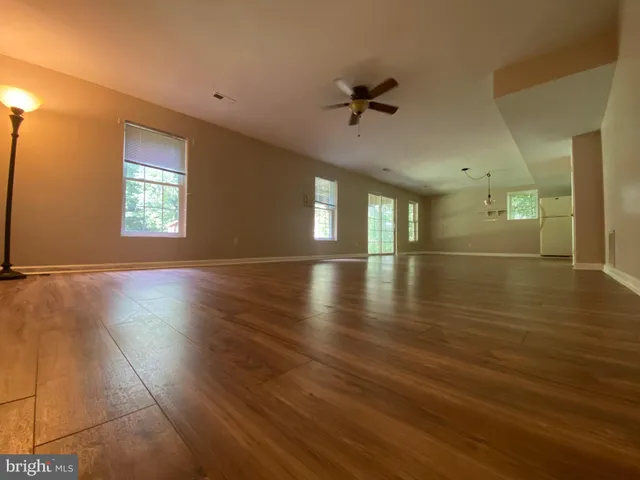 a view of an empty room with window and wooden floor