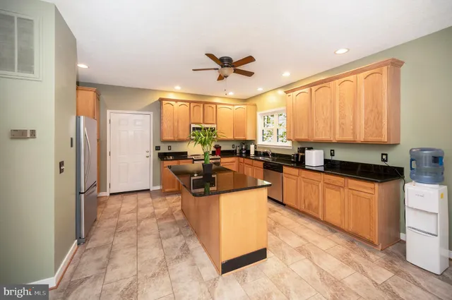 a large kitchen with stainless steel appliances granite countertop a stove a sink dishwasher and a refrigerator with wooden floor