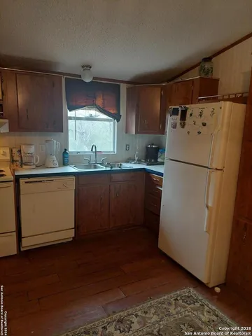 a kitchen with a refrigerator a sink and dishwasher with wooden floor