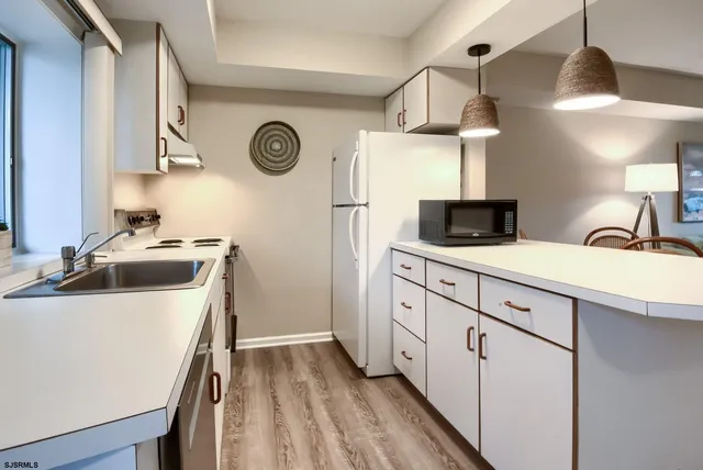 a kitchen with stainless steel appliances a sink a stove and a refrigerator with wooden floor