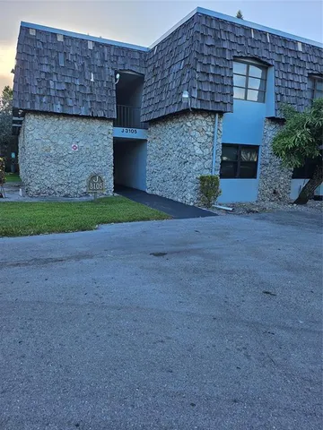 a front view of a stone house with a yard and garage