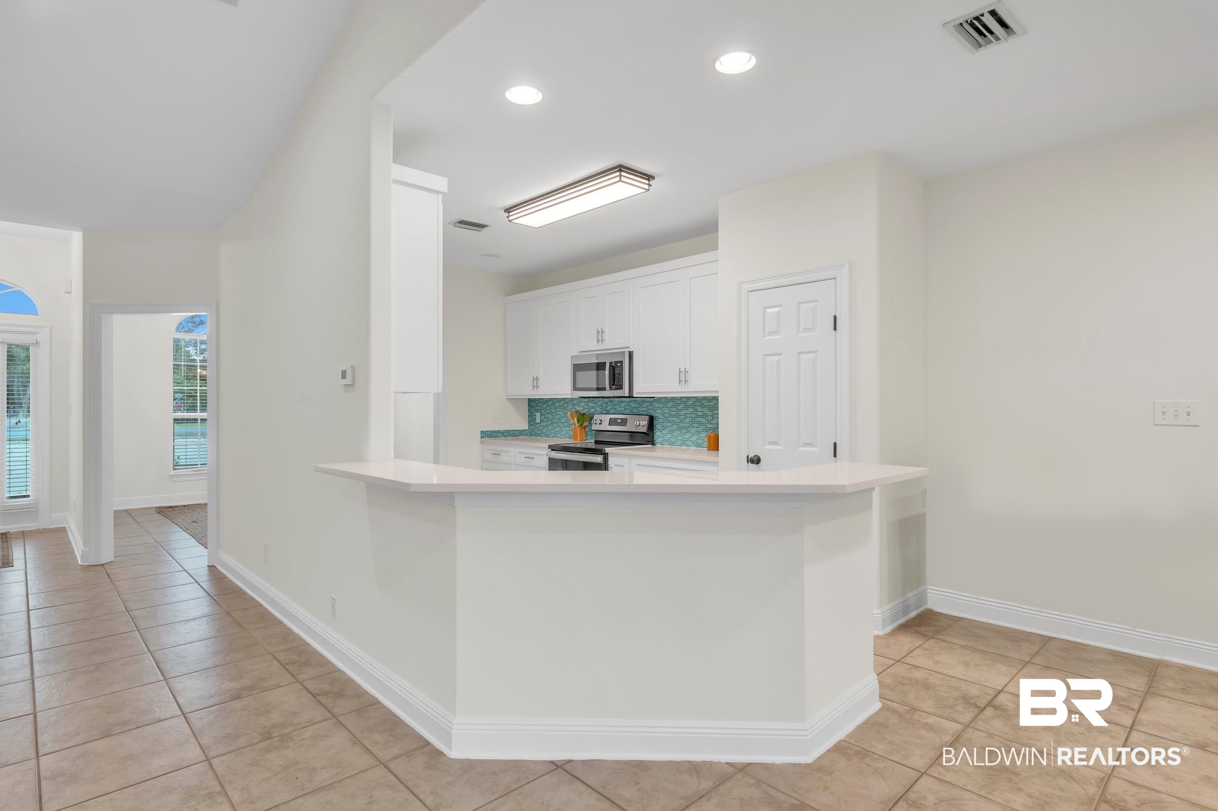 4606 Osprey Drive Orange Beach, AL 36561 - Photo 24 of 44 Kitchen featuring appliances with stainless steel finishes, light countertops, white cabinets, light tile patterned flooring, and recessed lighting, and a breakfast nook