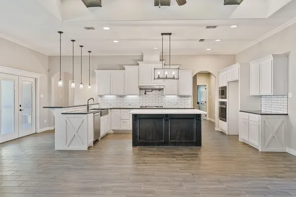 a kitchen with stainless steel appliances granite countertop a sink a stove a refrigerator and island with wooden floor