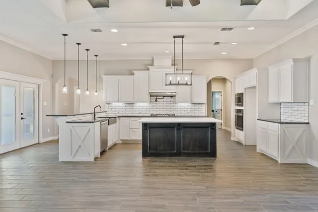 a kitchen with stainless steel appliances granite countertop a sink a stove a refrigerator and island with wooden floor