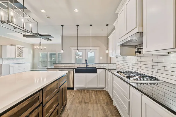 a kitchen with stainless steel appliances a sink a stove top oven a counter space and cabinets