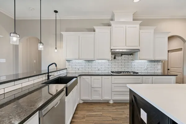 a kitchen with kitchen island granite countertop a sink a counter space appliances and cabinets