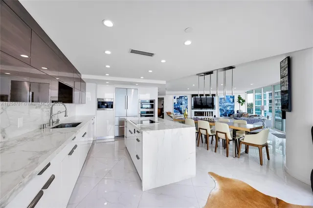 a large kitchen with lots of furniture a sink and a dining table with wooden floor