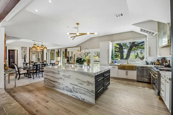 a view of a kitchen with kitchen island a stove a sink a dining table and chairs