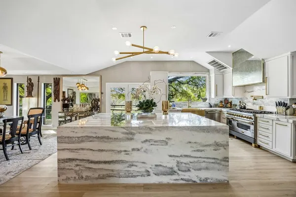 a kitchen with stainless steel appliances granite countertop a stove and chairs