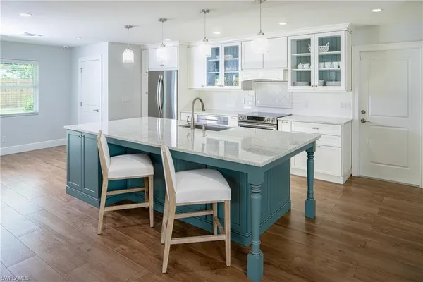 a kitchen with kitchen island a dining table chairs cabinets and wooden floor