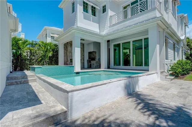 a view of a white building with a big yard and potted plants