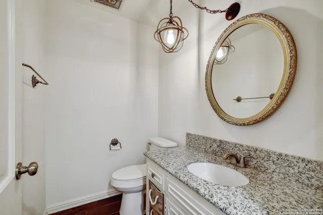 a bathroom with a granite countertop toilet sink and mirror