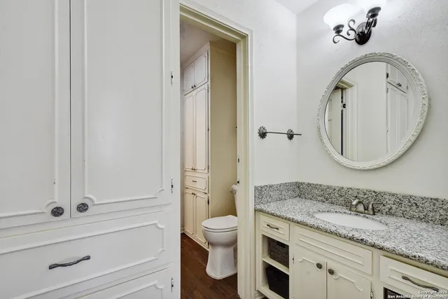 a spacious bathroom with a granite countertop toilet a sink and a mirror
