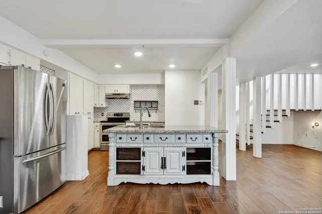 a kitchen with stainless steel appliances granite countertop a refrigerator oven a stove and a wooden floors