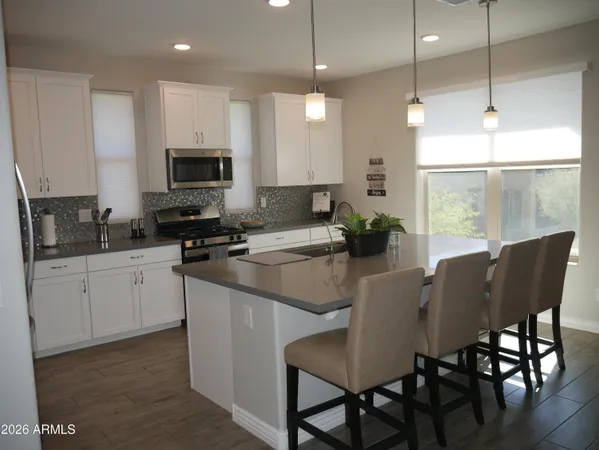 a kitchen with stainless steel appliances granite countertop a stove a sink a microwave a dining table and chairs