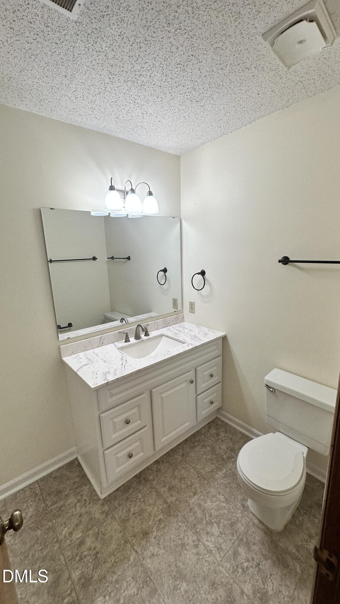 4705 Fargo Court, Unit B Raleigh, NC 27612 - Photo 7 of 9 a bathroom with a granite countertop toilet a sink and a mirror