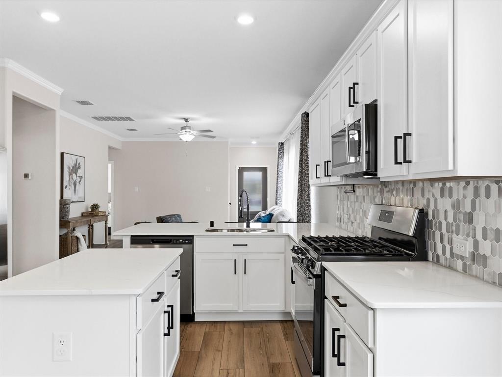 16936 Post Cedar Drive Justin, TX 76247 - Photo 7 of 30 Kitchen featuring white cabinetry with matte black hardware, white countertops, stainless steel appliances, a gas range, and wood-finish flooring