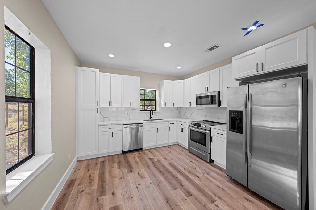28 Ruger Road Fredericksburg, TX 78624 - Photo 29 of 43 a kitchen with a refrigerator a sink and dishwasher with wooden floor
