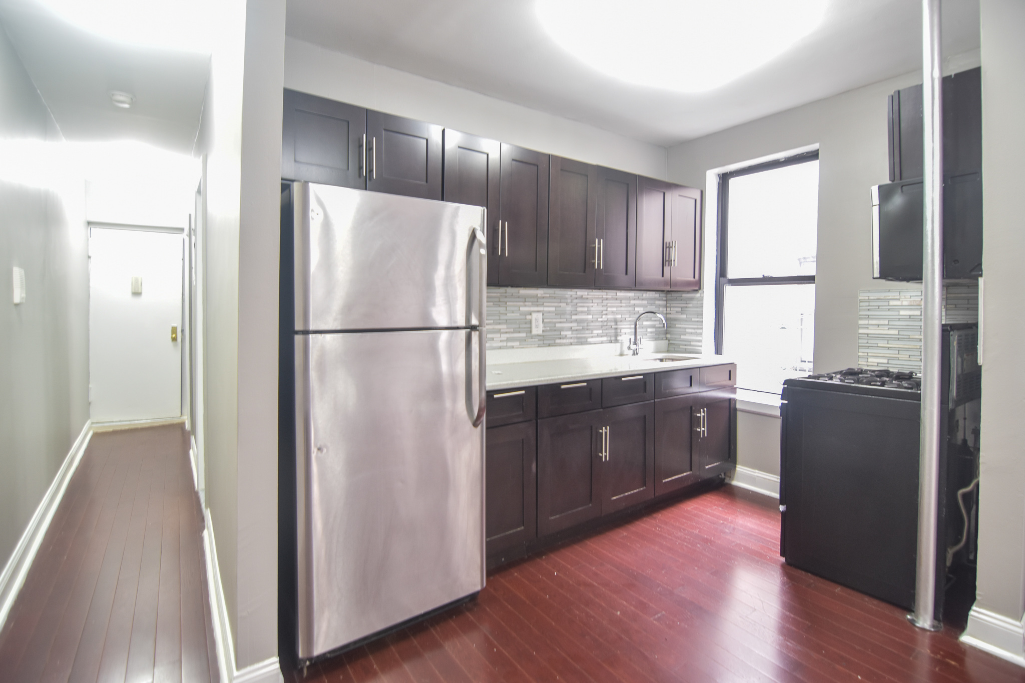 304 West 151st Street, Unit 12A Manhattan, NY 10039 - Photo 2 of 6 a kitchen with kitchen island wooden floors white cabinets and stainless steel appliances