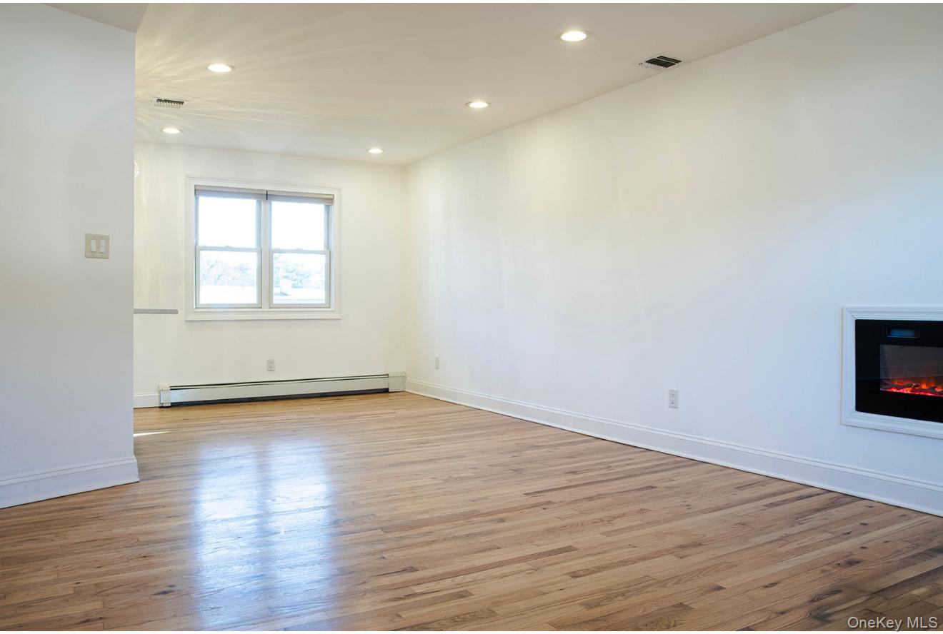 58 Hauppauge Road Hauppauge, NY 11788 - Photo 11 of 34 Unfurnished room featuring recessed lighting, light wood-style floors, a baseboard heating unit, and a glass covered fireplace