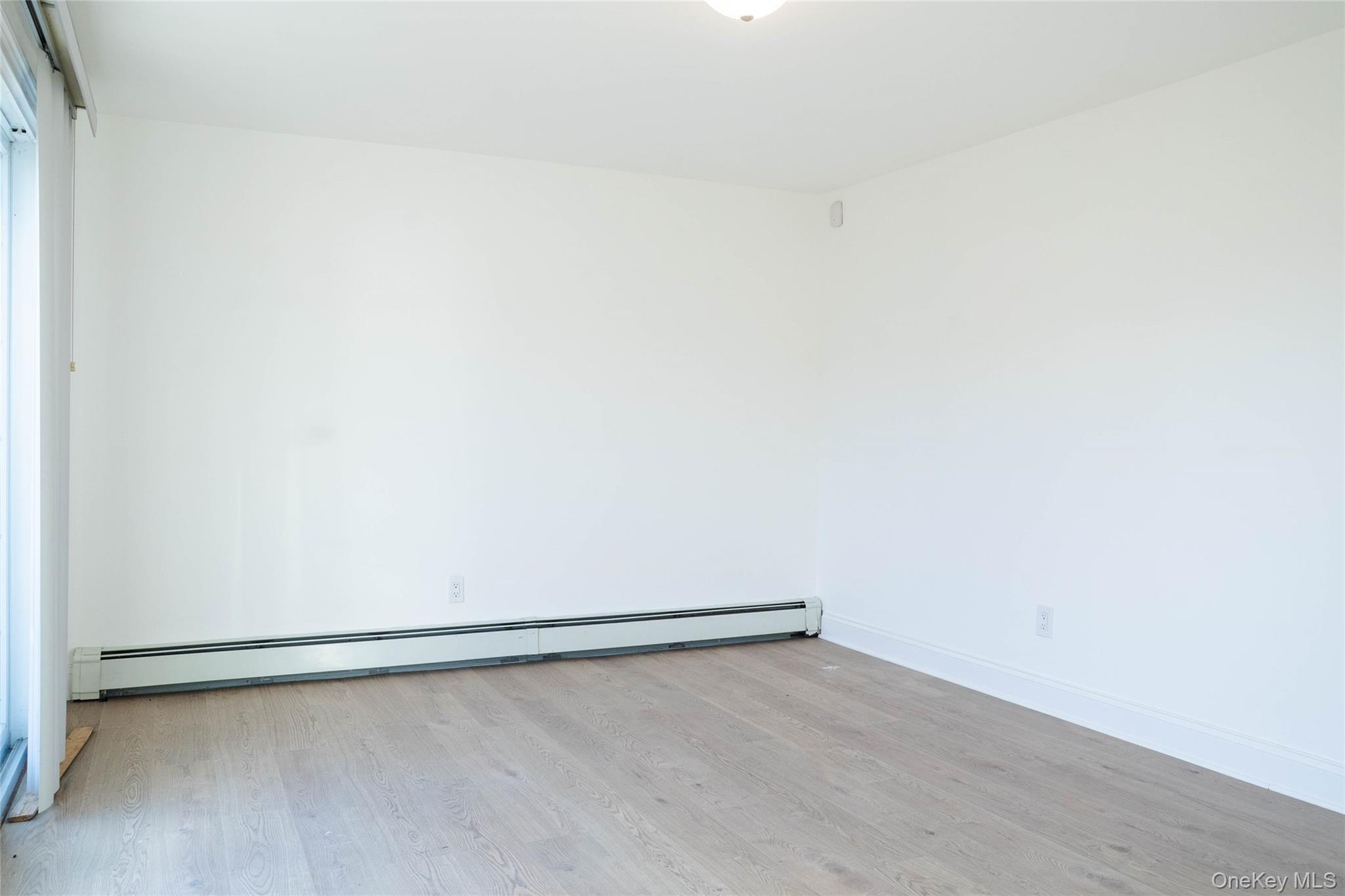 58 Hauppauge Road Hauppauge, NY 11788 - Photo 28 of 34 Empty room with a baseboard radiator and light wood-style floors