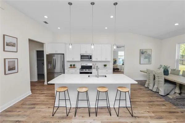 a kitchen with stainless steel appliances a refrigerator a stove a sink dishwasher and a refrigerator with wooden floor