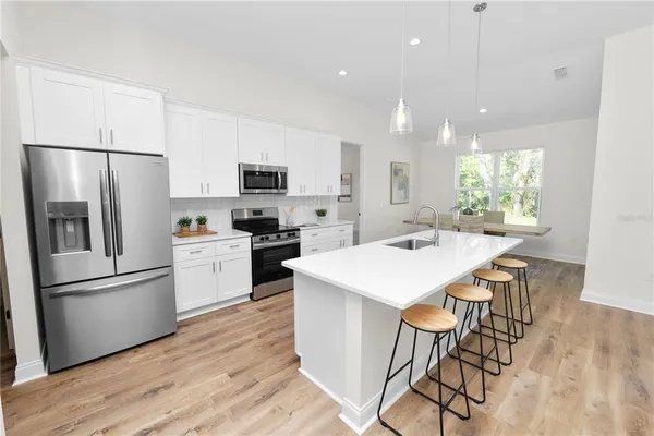 a kitchen with stainless steel appliances a table chairs refrigerator and a sink