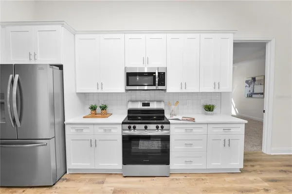 a large white kitchen with a lot of counter space and a wooden floor